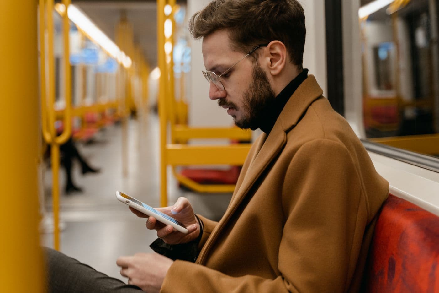 A man watching his phone on a subway train
