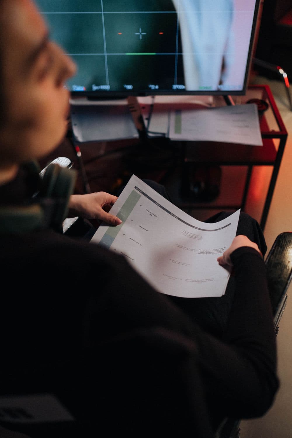Production team member reviewing a shot plan beside a video monitor