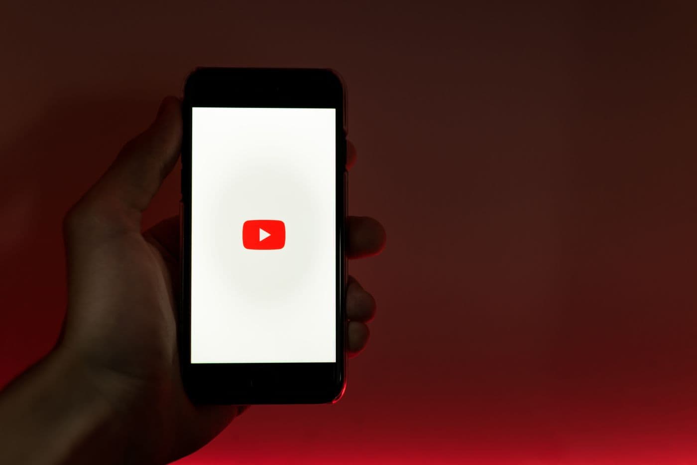 A hand holding a smartphone showing the YouTube app